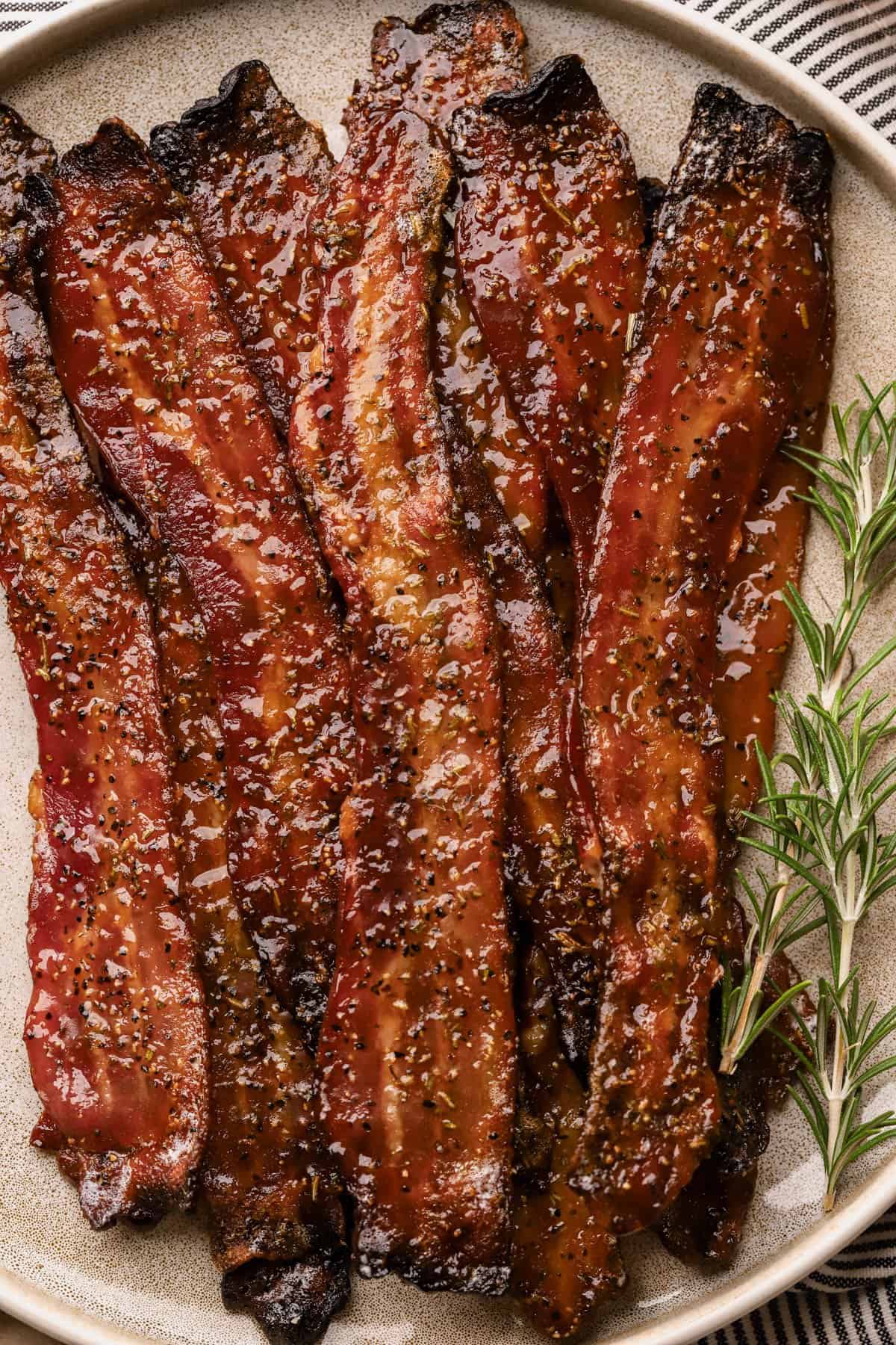 Maple bacon recipe with thick-cut bacon, brown sugar, maple syrup, coarse black pepper, paprika, and fresh rosemary.
