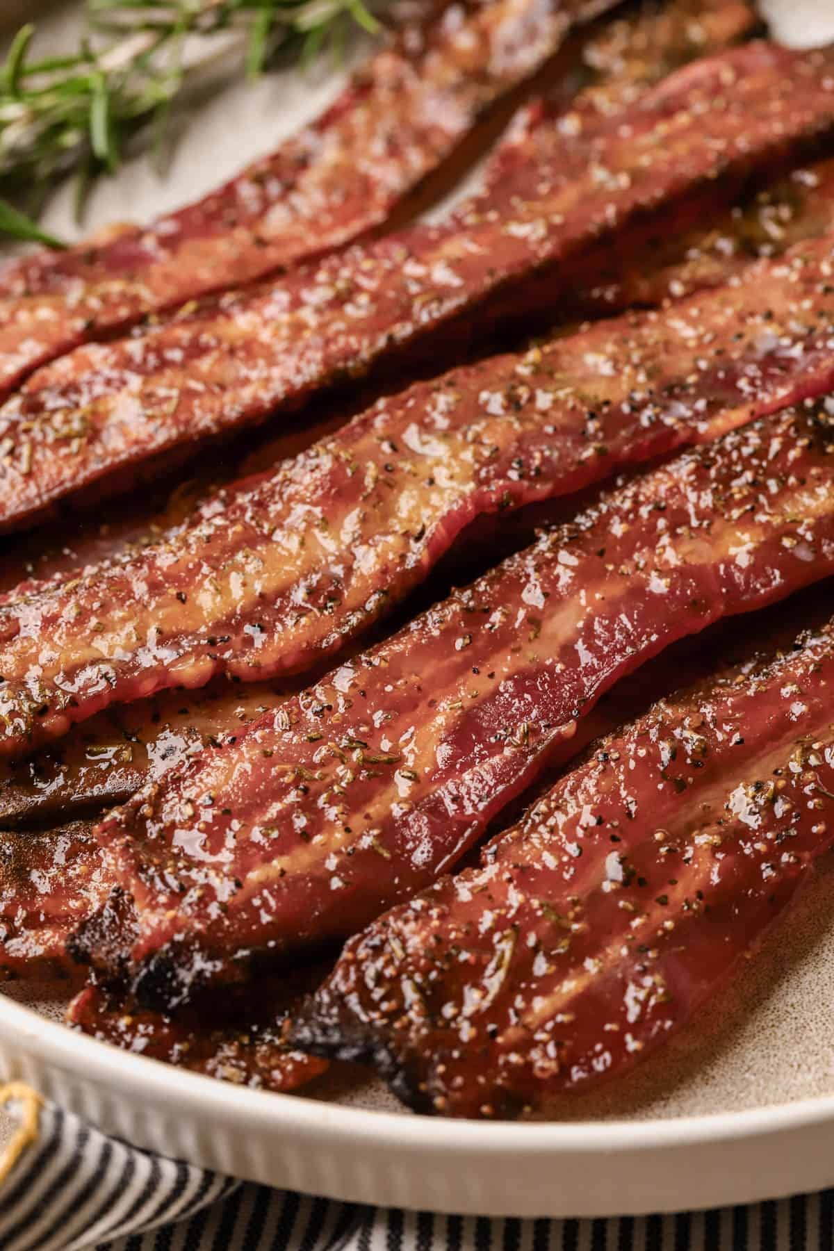 Candied bacon with thick-cut bacon, brown sugar, maple syrup, coarse black pepper, paprika, and fresh rosemary.
