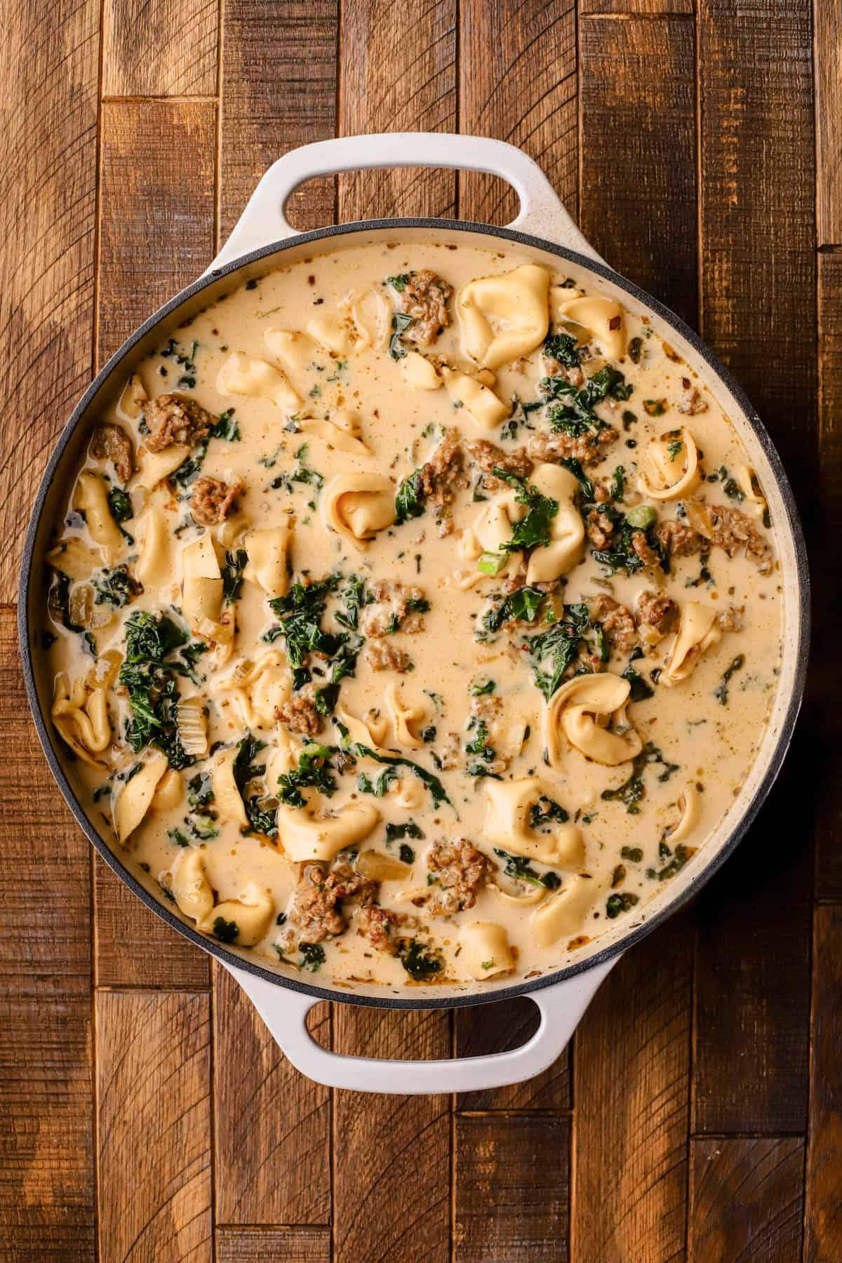 Tuscan tortellini soup is made with Italian sausage, kale, cheese tortellini, red pepper flakes, onions, garlic, celery, heavy cream and parmesan cheese.