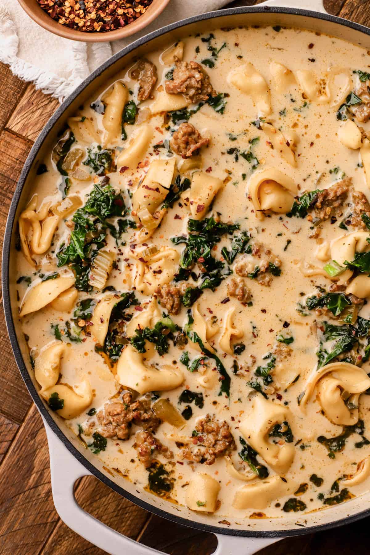 Tuscan tortellini soup is made with Italian sausage, kale, cheese tortellini, red pepper flakes, onions, garlic, celery, heavy cream and parmesan cheese.
