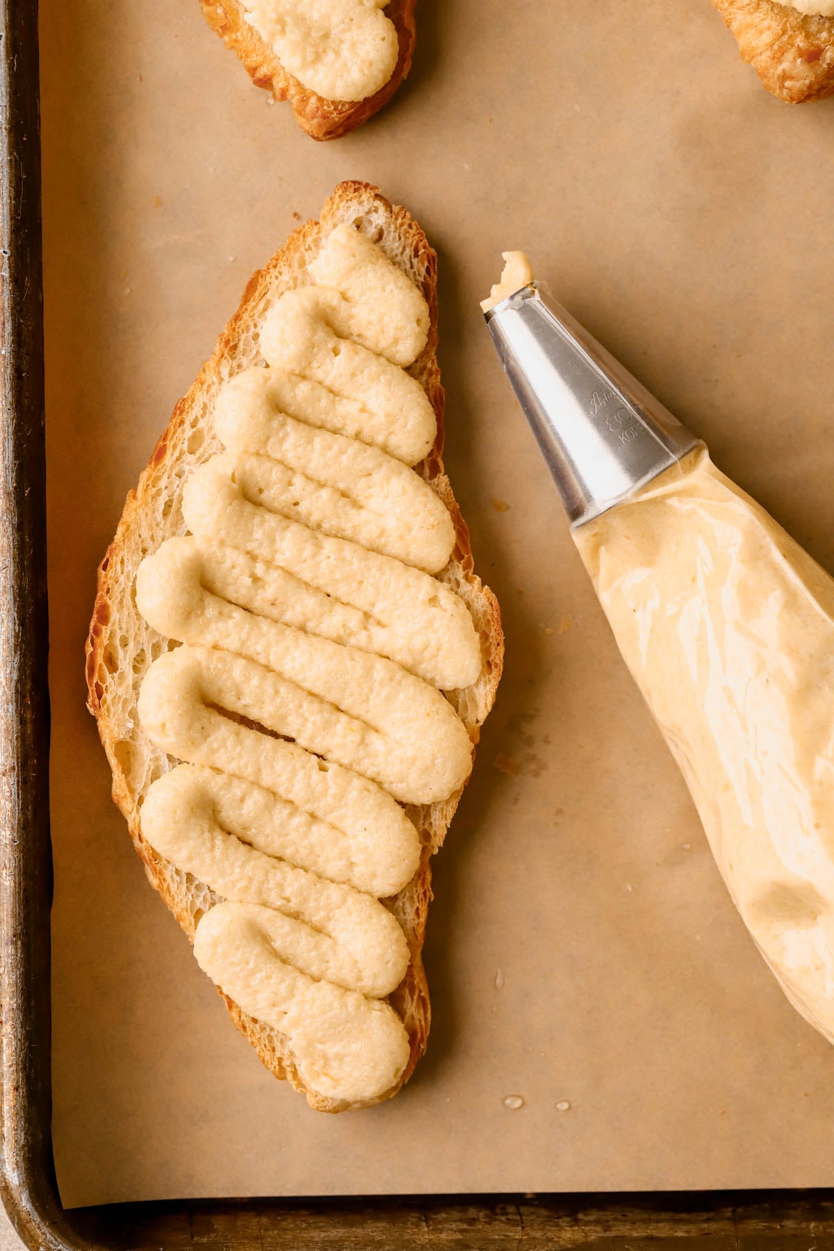 Close up of creamy frangipane filling, piped onto bottom half of croissant. 