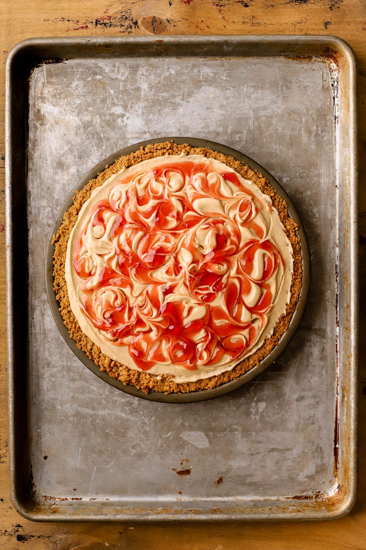 Nutter butter pie shell filled with peanut butter crust and swirls of strawberry jam. 