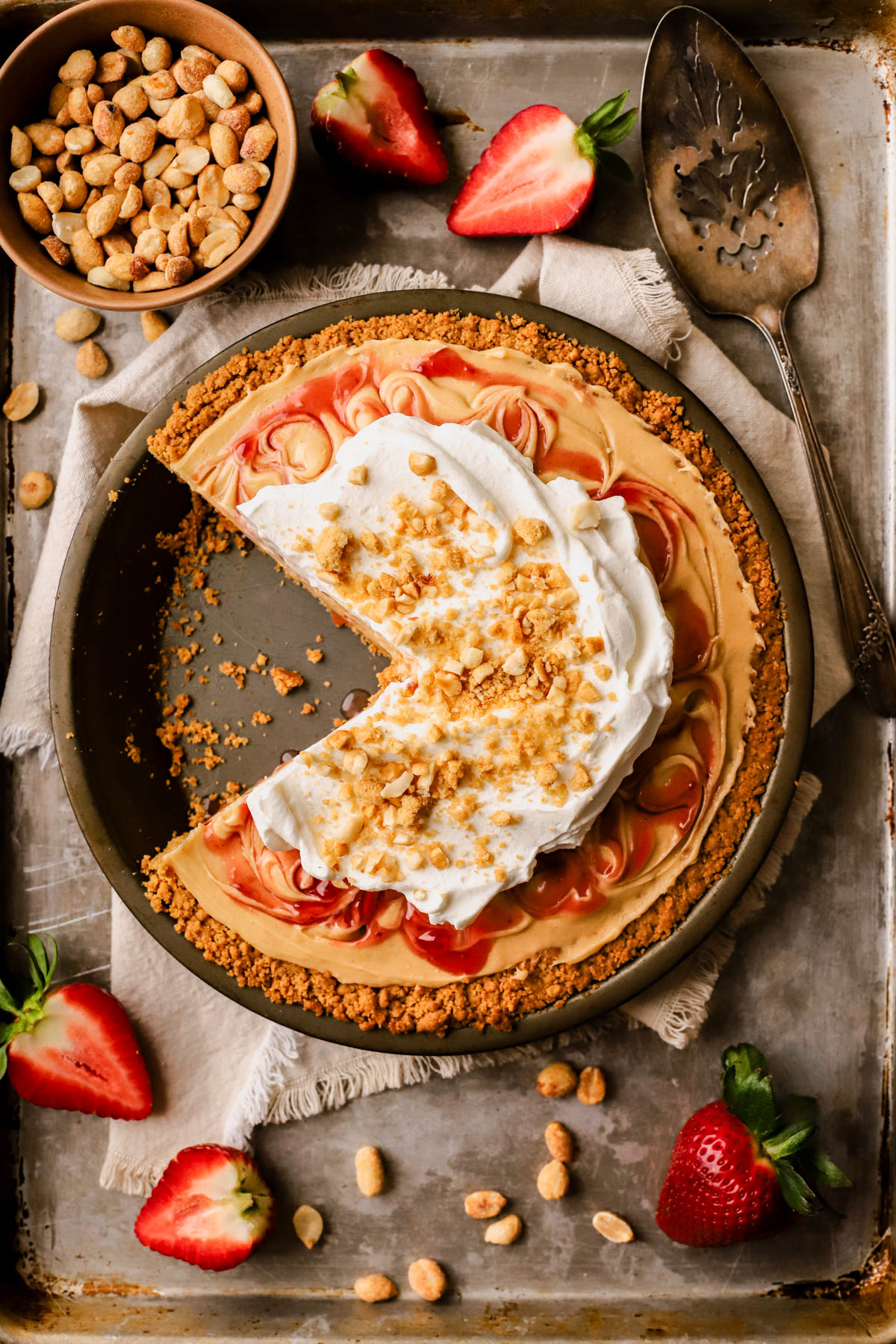 Sliced peanut butter and jelly pie with vanilla whipped cream, chopped peanuts, strawberry jam, and Nutter Butter cookie crumbs. 